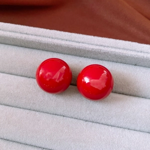 Close-up of elegant red spherical stud earrings displayed in a grey velvet jewelry box