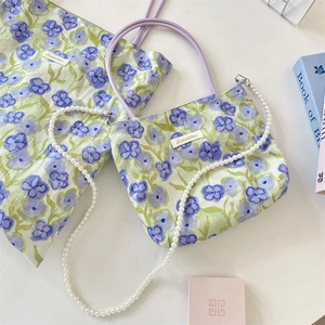 Dettaglio della borsa in tela floreale con stampa di fiori viola e catena di perle