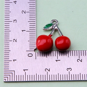 Detailed view of red cherry alloy pendant with dimensions measured on a ruler scale