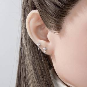 Silver cross stud earring with zircon inlay and cone pendant worn by model in a close-up view