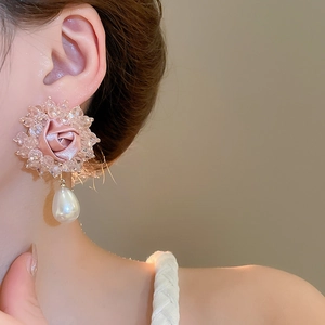 Close-up of pink satin flower earrings with crystal accents and water-drop pearl pendant