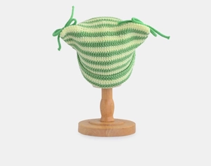 Detail of green striped crochet beanie with cat ears on a wooden stand display