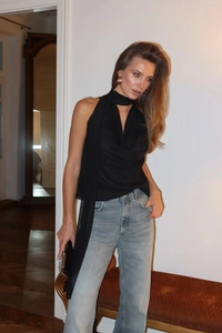 Detail eines eleganten schwarzen Neckholder-Satinoberteils mit fließender Textur am Model