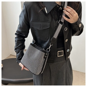 Detail of rhinestone shoulder bag featuring wide patterned strap and leather jacket style