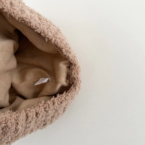 Detailaufnahme einer plüschigen Baby-Wintermütze mit Strickfutter für Wärme und Komfort