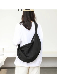 Vista posteriore di una grande borsa a tracolla in nylon nero indossata in uno stile urbano