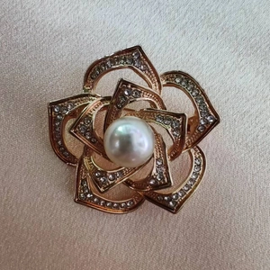 Macro shot of gold hollowed-out camellia brooch with crystal petals and pearl center