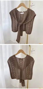 Detail of a brown knitted shawl vest with hollow patterns and a front tie decoration