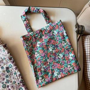 Detail of floral cotton handbag showing dense pattern and antique bronze metal snap button