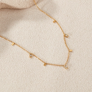 Detail of gold-tone chain necklace with square metal charms and clear zircon stones