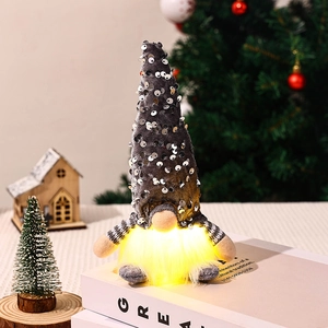 Close-up of glowing sequin gnome doll on books with warm festive Christmas background