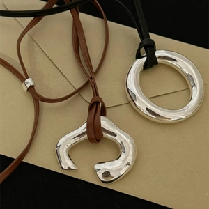 Polished silver circular and U-shaped pendant necklace on black and brown leather cords