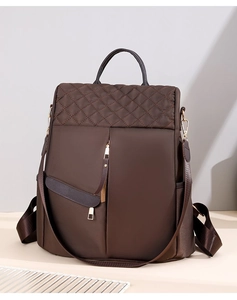 Macro view of dark brown quilted nylon backpack with gold hardware and leather tassels