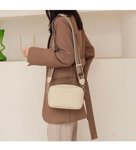 Detail of beige litchi grain PU leather crossbody bag with a striped wide shoulder strap