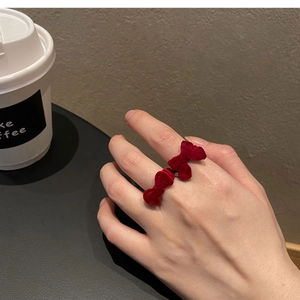 Detail of red velvet bow ring worn on finger in a stylish cafe setting for women