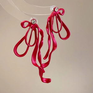 Detailed close-up of oversized magenta matte bow earrings with crystal stud and metal texture