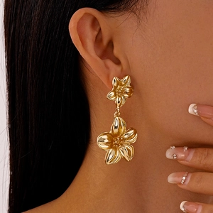 Nahaufnahme von eleganten goldenen Doppelblüten-Ohrhängern an einem Model im Luxusstil