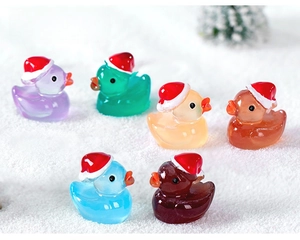 Close-up of colorful translucent resin ducks wearing mini Santa hats for micro landscapes