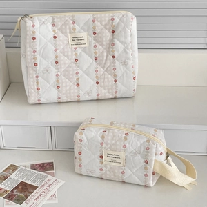 Detail of two beige quilted cotton toiletry bags with pink floral stripes and zipper handle