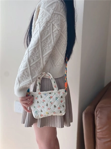 Detailed shot of quilted floral mini bag with a colorful hand-woven shoulder strap