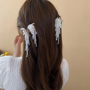 Detail view of artificial pearl tassel hair clips worn on elegant wavy long hair