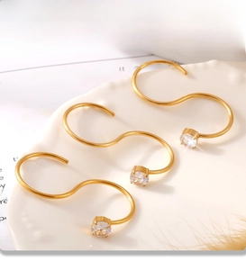 Macro shot of three PVD gold-plated S-shaped ear cuffs with 3A cubic zirconia in a ceramic tray