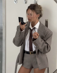 Detail of a brown plaid suit with blazer and shorts featuring retro neutral styling