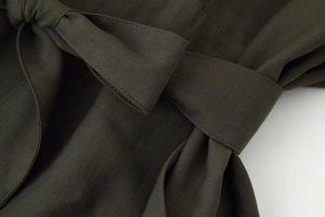 Vue macro du tissu sergé vert olive avec détail de ceinture nouée à la taille