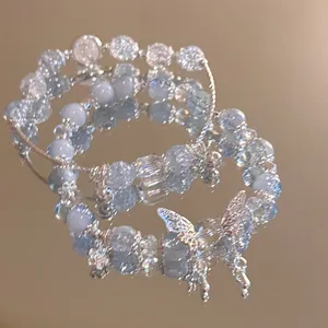 Macro shot of blue crackle bead bracelet set with a silver butterfly charm on a mirror