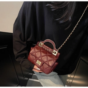 Detail of wine red quilted handbag with golden twist lock and luxury chain strap