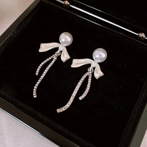 Elegant bow pearl drop earrings with sparkling tassels on a black velvet jewelry box