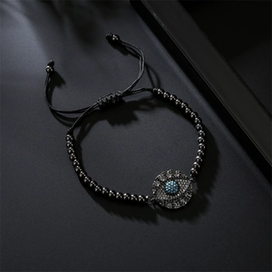 Detailed close-up of a black beaded evil eye bracelet with blue zircon inlay on dark surface