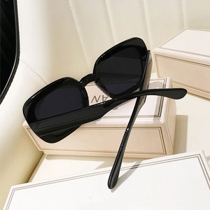 Detail of square oversized polarized sunglasses resting on white decorative gift boxes