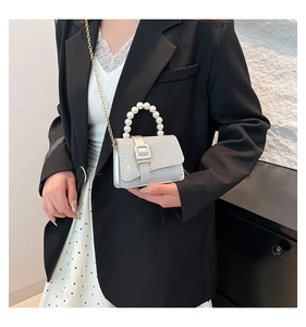 Close-up of shimmering silver sequin mini bag with large pearl handle and gold chain strap