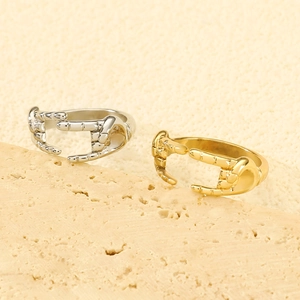 Macro shot of gold and silver gesture-shaped rings on a textured beige stone background