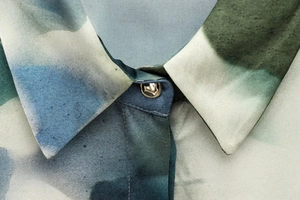 Gros plan du col d'une chemise en satin avec imprimé abstrait et bouton bille argenté