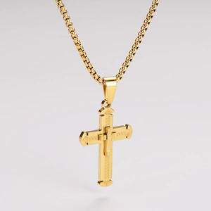 Detailed macro view of a gold-plated cross pendant with intricate engraved patterns and bead chain
