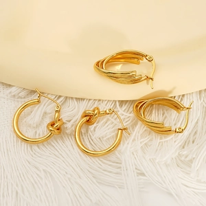 Elegant gold-tone multi-layer and knotted hoop earrings displayed on soft textured background