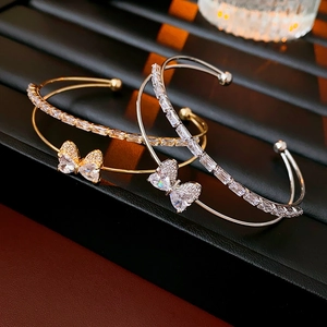 Detailed close-up of gold and silver butterfly cuff bracelets with cubic zirconia accents