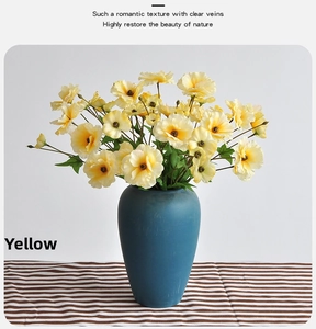 Detailed macro view of yellow butterfly ranunculus petals and matte blue ceramic vase