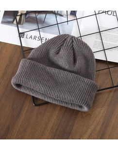 Detail of dark grey knitted beanie showing fine ribbed texture on a wooden table