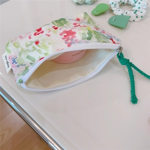 Detail view of floral cotton pouch showing interior storage with makeup and simple wish label