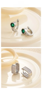 Close-up of elegant silver hoop earrings with green gemstone and pavé diamonds