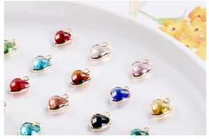 Macro shot of colorful faceted crystal heart pendants with gold frames on white plate