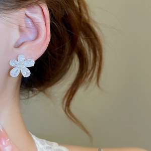 Macro shot of silver floral earrings with sparkling cubic zirconia and white pearls