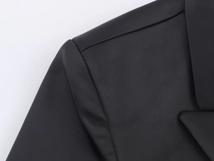 Dettaglio del colletto del blazer in raso nero con cuciture fini e texture opaca