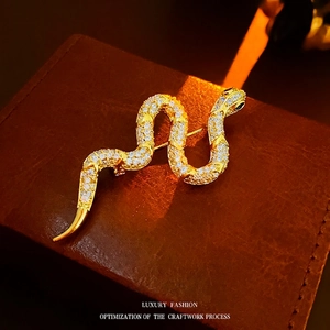 Luxurious gold-plated snake brooch with sparkling white zircons on a leather box