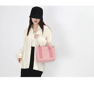 Detailed view of pink canvas tote bag with front zipper pocket shown on a model