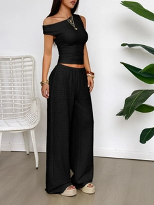 Detail of black one-shoulder cropped top and wide-leg trousers set with textured fabric
