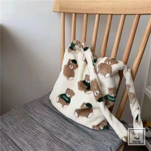 Detail of plush white tote bag with brown bears on a grey chair in warm light